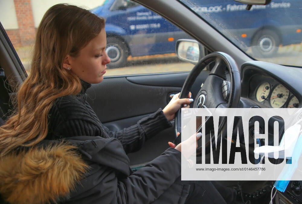 Young woman driving car while looking at her mobile phone young woman driving car while looking at her mobile phone