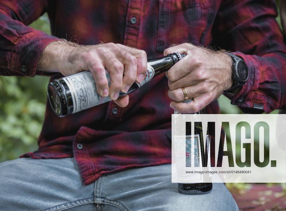 Man with red shirt opens beer bottles, Munich, Bavaria, Germany, Europe