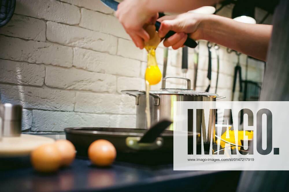 Woman housewife prepares fried eggs with ham and vegetables in his kitchen. egg breaks, adding to the pan model released, Symbolfoto, 25.09.2021,