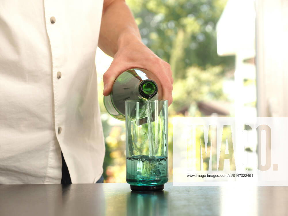 Mid aged man pouring water into a glass, healthy eating concept, clean and fresh