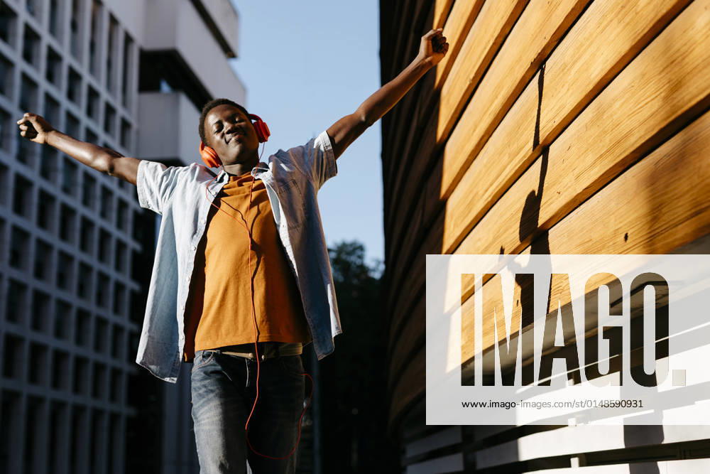Cheerful man with arms outstretched enjoying music through headphones model released, TCEF02142