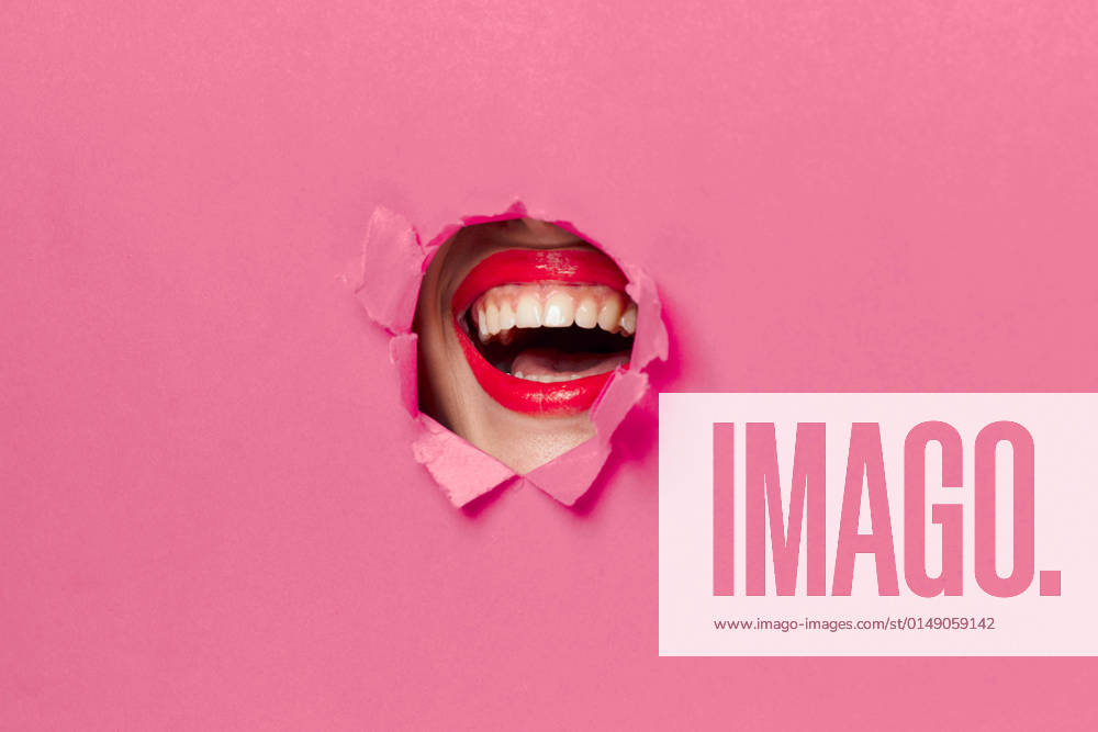 IMAGO Creative, Lifestyle, Barbiecore IMAGO Creative: Guten Rutsch cheerful woman poster hole pink background and red lips cheerful woman poster hole pink background and red lips. High quality photo
