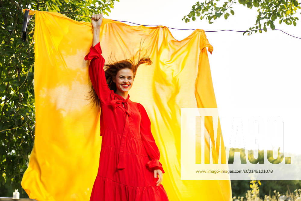 Woman in a red dress with hands raised up yellow fabric nature woman in a red dress with hands raised up yellow fabric nature. High quality photo
