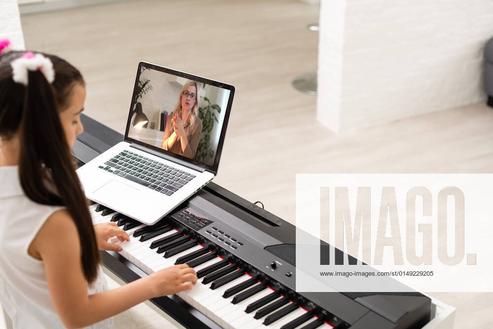 IMAGO Creative: Bildung, Musikerziehung little girl play piano in class education with laptop in home online learning in covid-19 crisis quarantine little girl play piano in class education with laptop in home online learning in covid-19 crisis quarantine.