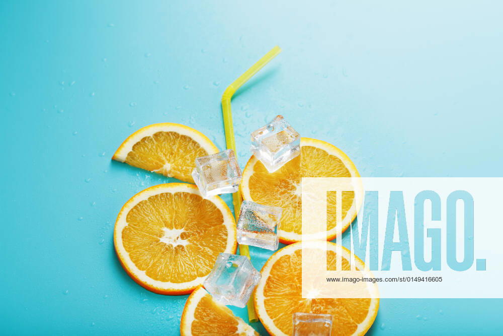 Orange slices and ice cubes with a straw on a blue background in the shape of a cocktail. Orange slices and ice cubes with a straw on a blue background in the shape of a cocktail. Top view, free space