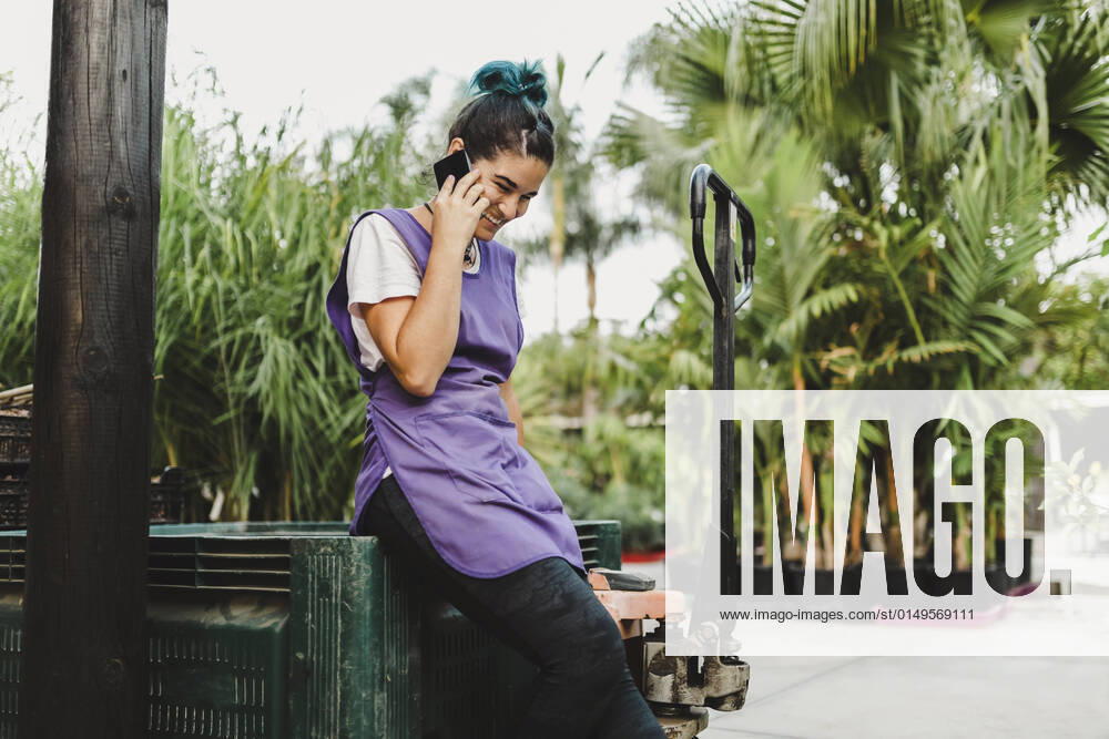IMAGO Creative: Business, Innovative Technologie-Lösungen Happy female owner talking on smart phone in garden center Spain, Andalucia, model released, property released
