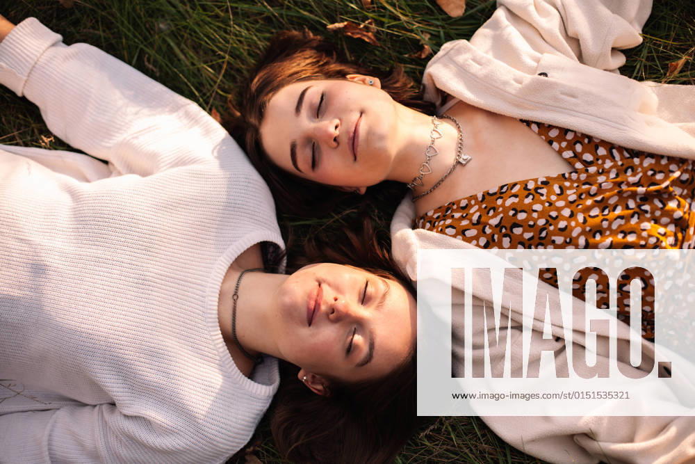 Overhead view of two happy young women lying on grass with eyes closed CR_DMBE220219-918561-01 ,model released, Symbolfoto