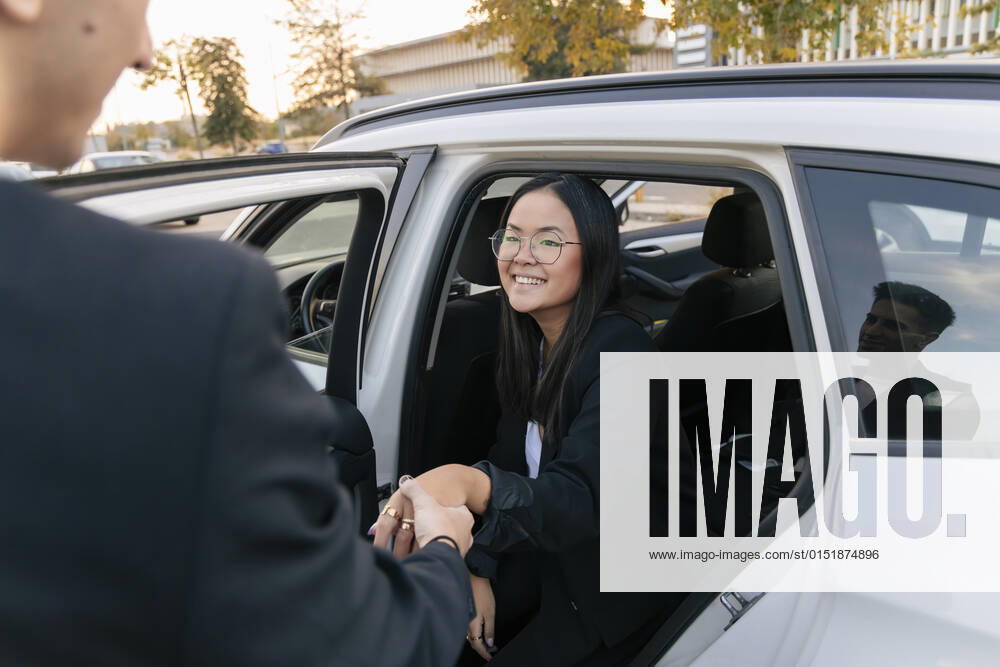 Businessman assisting smiling businesswoman disembarking from car model released, JRVF02584