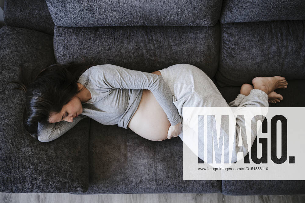 Pregnant woman lying on sofa at home model released property released, EBBF05624