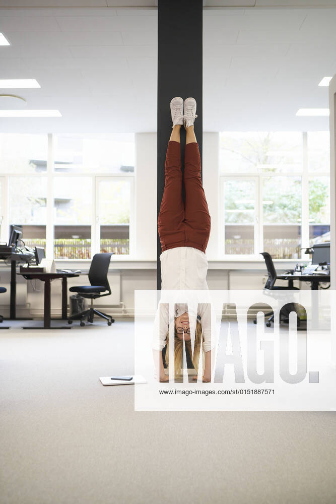 Businesswoman doing handstand in front of a column at office model released property released, JAHF00175