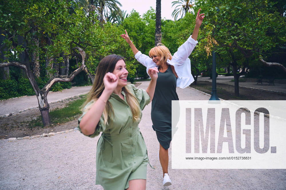 IMAGO Creative: Sommer, Sommertage im Stadtpark Delighted female friends walking together on path while having fun in park with green trees on summer day in city, Model released GermanLinares_OfficeWomen_23.jpg