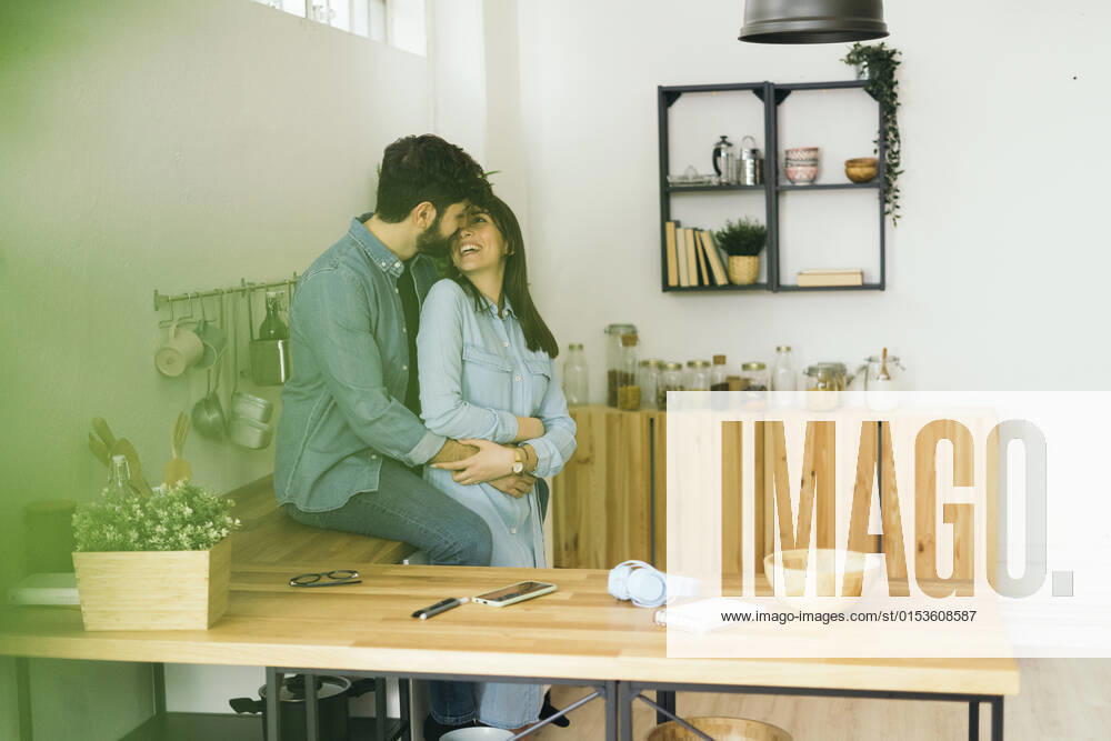 Smiling young couple embracing each other in kitchen at home model released property released, GIOF14882