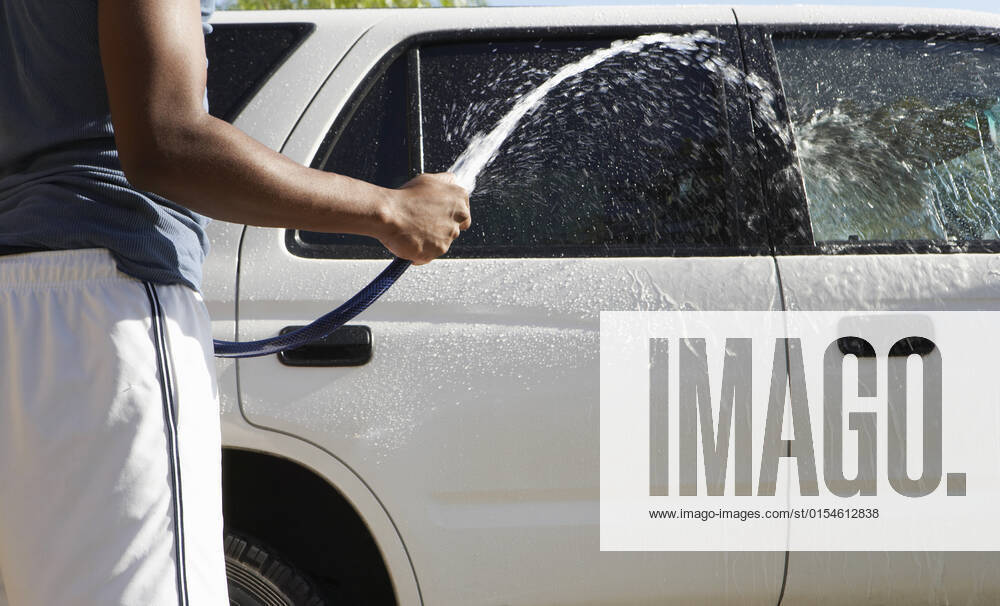 Man Cleaning Car With Water Hose, model released, , 10042732.jpg, outdoors, day, mid section, standing, holding, casual clothing, hand, 20-25 years, young adult man, one person only, summer, car, chores, rinsing, washing, car was, hose, water, splashing, cleaning, 20s, adult, one, person,