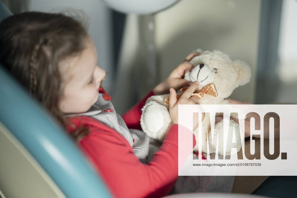 Little girl sitting on dental chair with stuffed toy at medical clinic model released, Symbolfoto property released, JCCMF05858