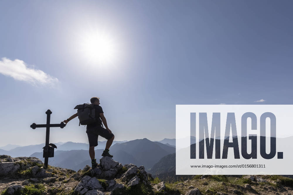 Germany, Bavaria, Sun shining over silhouette of male hiker standing by Fockenstein summit cross model released, Symbolfoto, FOF13102
