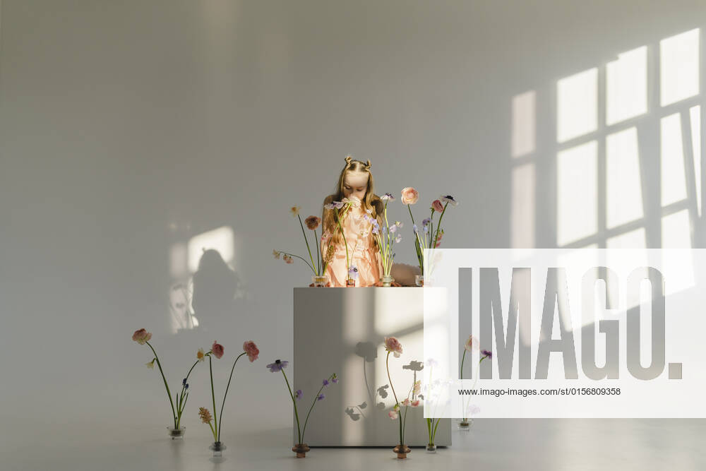 Girl smelling flower at table in front of wall model released, Symbolfoto property released, SEAF00717
