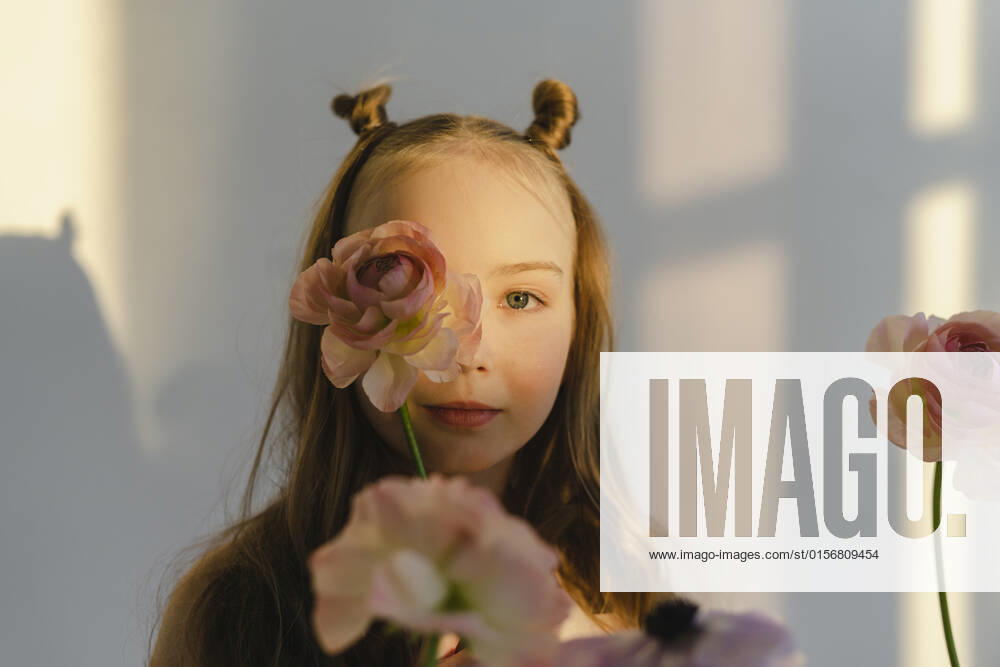 Cute girl holding flower on face standing by white wall model released, Symbolfoto property released, SEAF00740