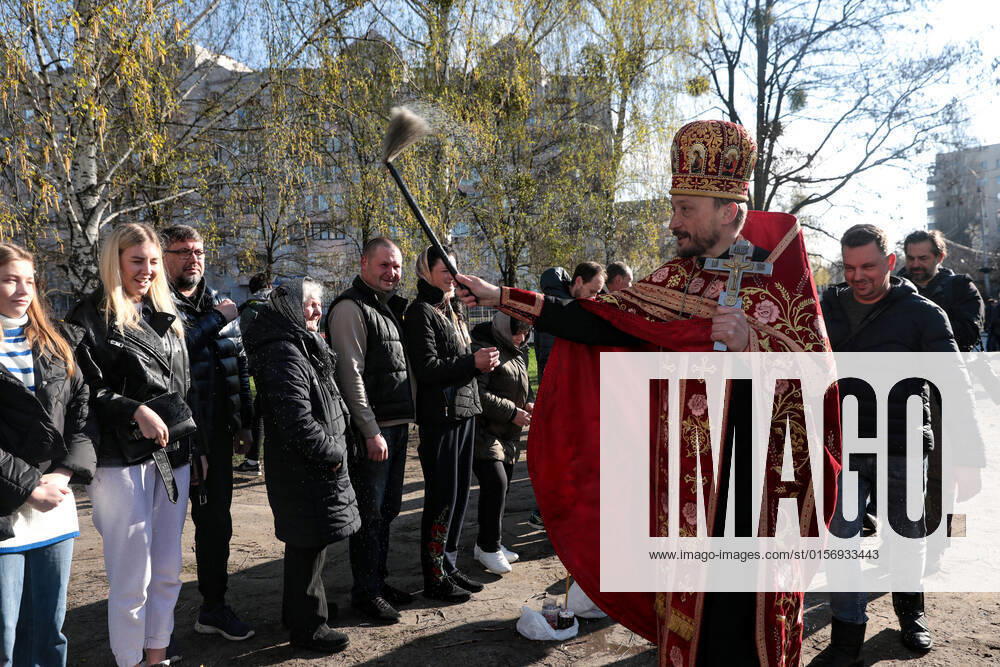 BUCHA, UKRAINE - APRIL 24, 2022 - A priest blesses people and their baskets with holy water outside the Church of Saint Andrew the First-Called Apostle during the Orthodox Easter celebration in Bucha that is recovering from the war crimes committed by Russian troops after its liberation from Russian invaders, Kyiv Region, northern Ukraine. Easter service in Bucha