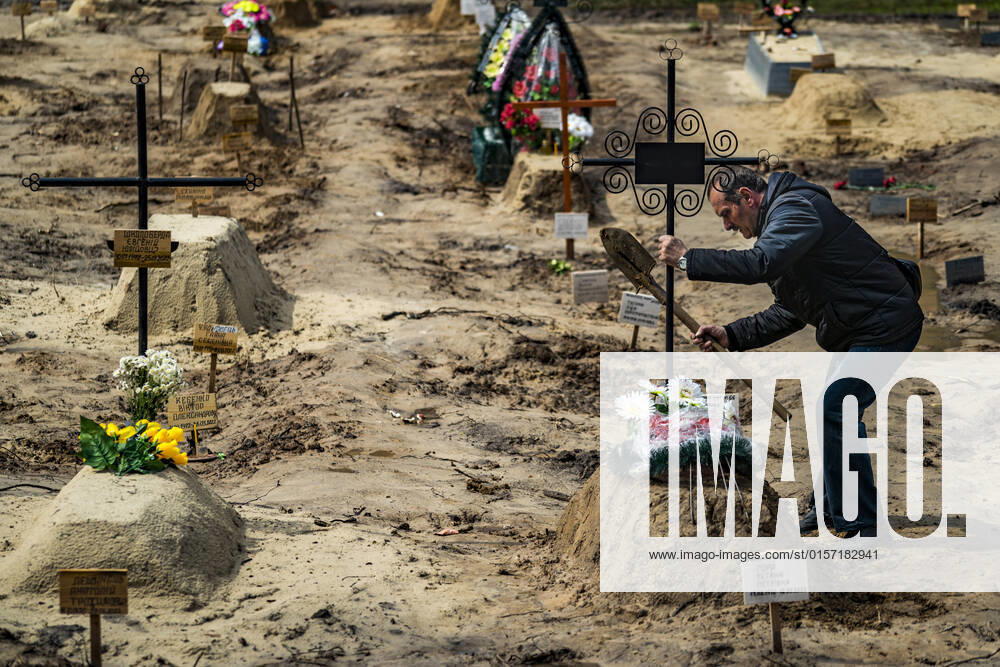 A man holds a cross after burying a relative killed during the occupation of the russian army in Chernihiv. Corpses have to wait until their final destination in a cementery, and usually are buried by a relative. Chernihiv Ukraine - ZUMAa131 20220426_zap_a131_014