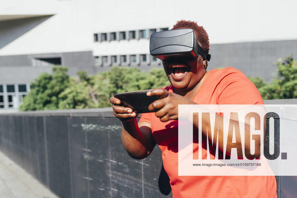 IMAGO Creative: Business, Innovative Technologie-Lösungen Happy woman wearing virtual reality simulator using smart phone on sunny day model released, Symbolfoto, MEUF05489