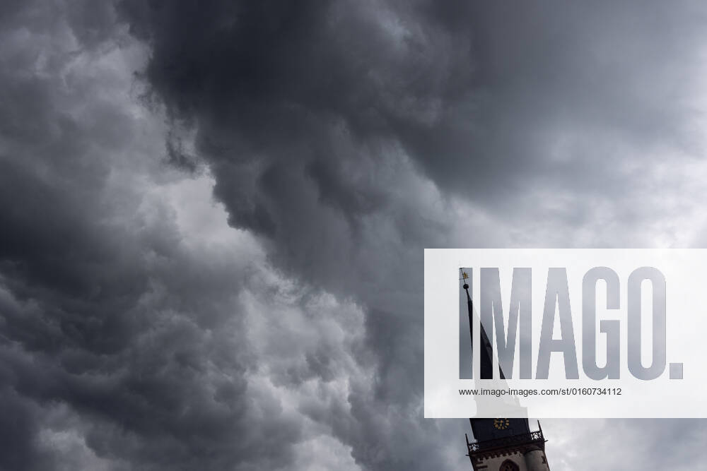 Dark clouds over the church tower Dark clouds of a shower are seen in the evening in the sky above the steeple of the Catholic Church St Ursula in Oberursel , Oberursel Hesse Germany