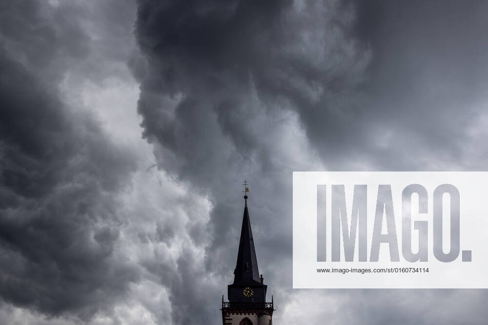 Dark clouds over the church tower Dark clouds of a shower are seen in the evening in the sky above the steeple of the Catholic Church St Ursula in Oberursel , Oberursel Hesse Germany