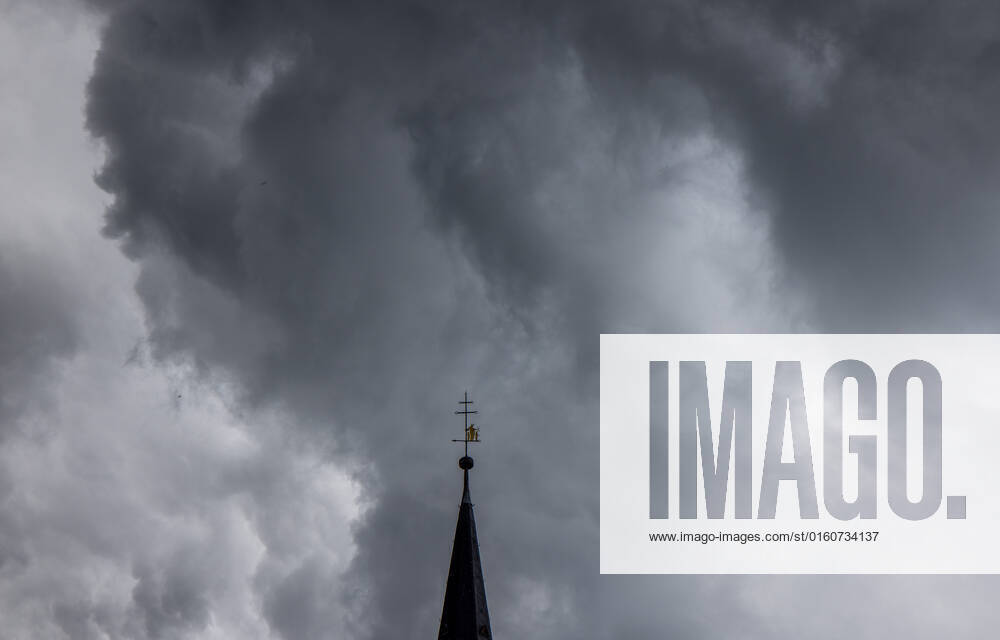 Dark clouds over the church tower Dark clouds of a shower are seen in the evening in the sky above the steeple of the Catholic Church St Ursula in Oberursel , Oberursel Hesse Germany