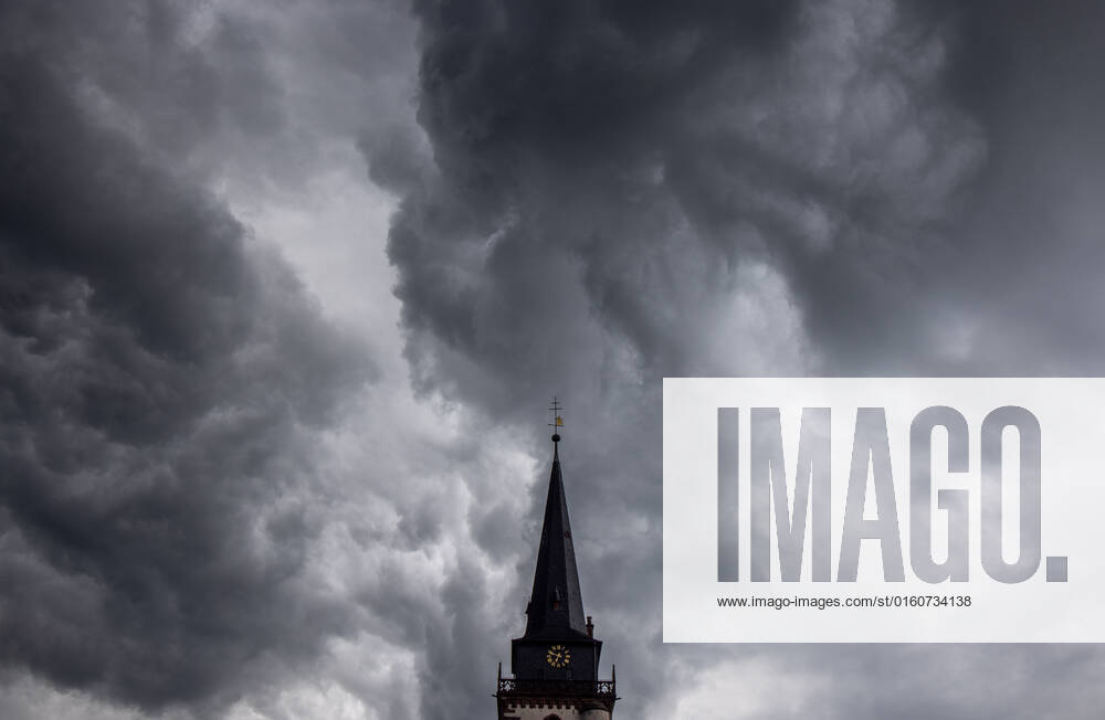 Dark clouds over the church tower Dark clouds of a shower are seen in the evening in the sky above the steeple of the Catholic Church St Ursula in Oberursel , Oberursel Hesse Germany