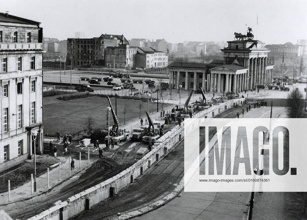 Berlin wall reinforced. Under the watchful eye of Communist police, East german workers near the Brandenburg Gate reinforce the wall dividing the city. Since erecting the wall on August 13, 1961, to stop the flow of East Germans into West Berlin, the East German Communists have added bunkers, spotlights and firing and observation posts. 1062_05_M_-12888-