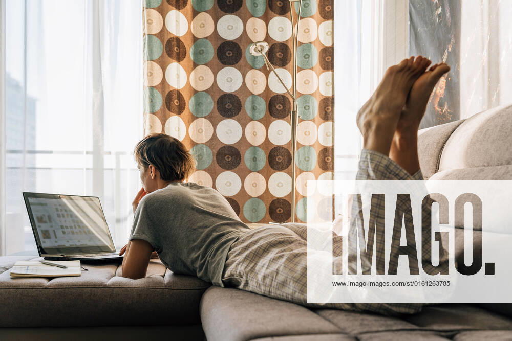 IMAGO Creative: Business - Work-Life Balance A short-haired woman lies at home on the couch and works on a laptop Vilnius, Vilnius County, Lithuania CR_EDSAHG220525-986846-01 ,model released, Symbolfoto