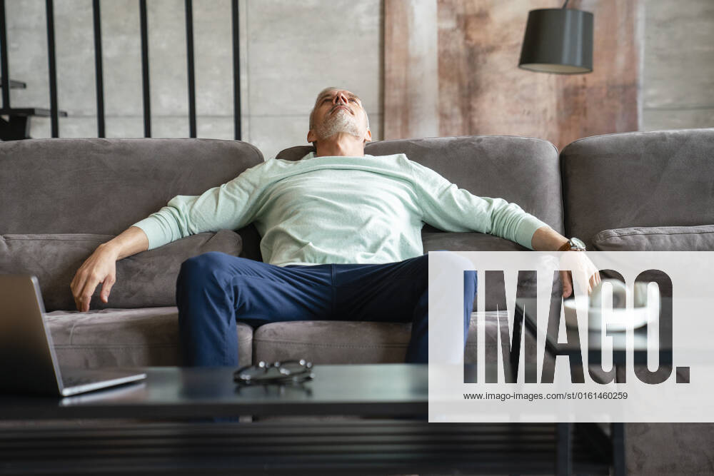 Tired man resting on sofa in living room at home model released, Symbolfoto property released, VPIF06071