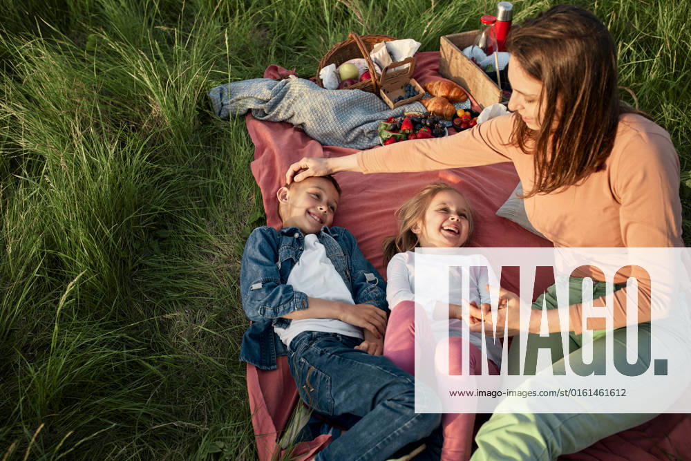 Mother sitting by happy children on picnic blanket model released, Symbolfoto, ZEDF04602