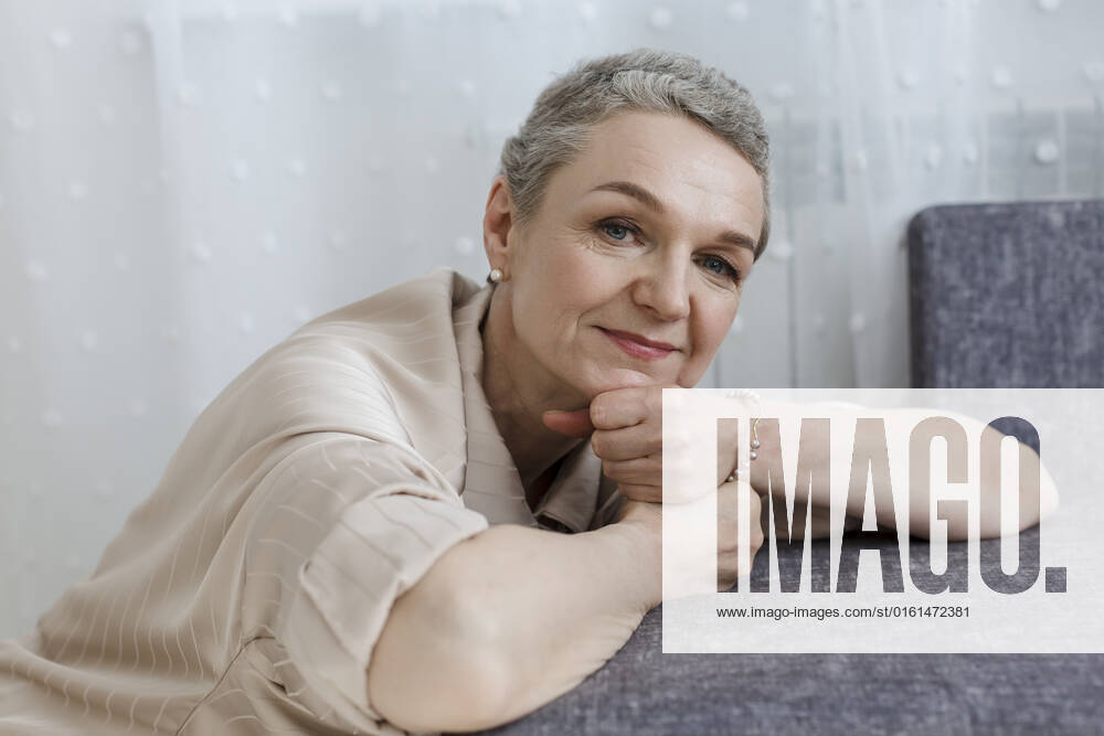 Portrait of mature woman with short grey hair leaning on couch model released, Symbolfoto property released, LLUF00673