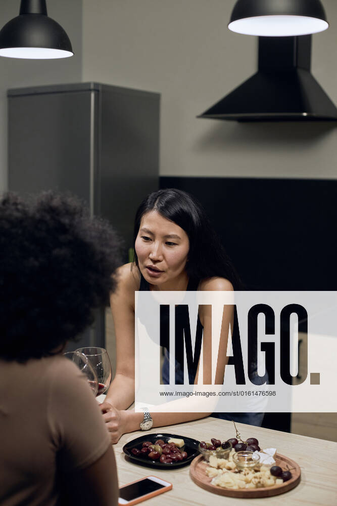 IMAGO Creative, Food, Tapas Young woman talking with girlfriend in kitchen at home model released, Symbolfoto property released, DSHF00484