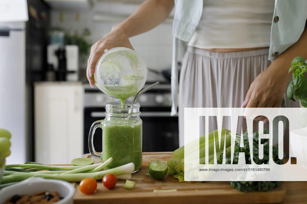 Hand of woman pouring smoothie in mason jar from juicer at home model released, Symbolfoto property released, TYF00186