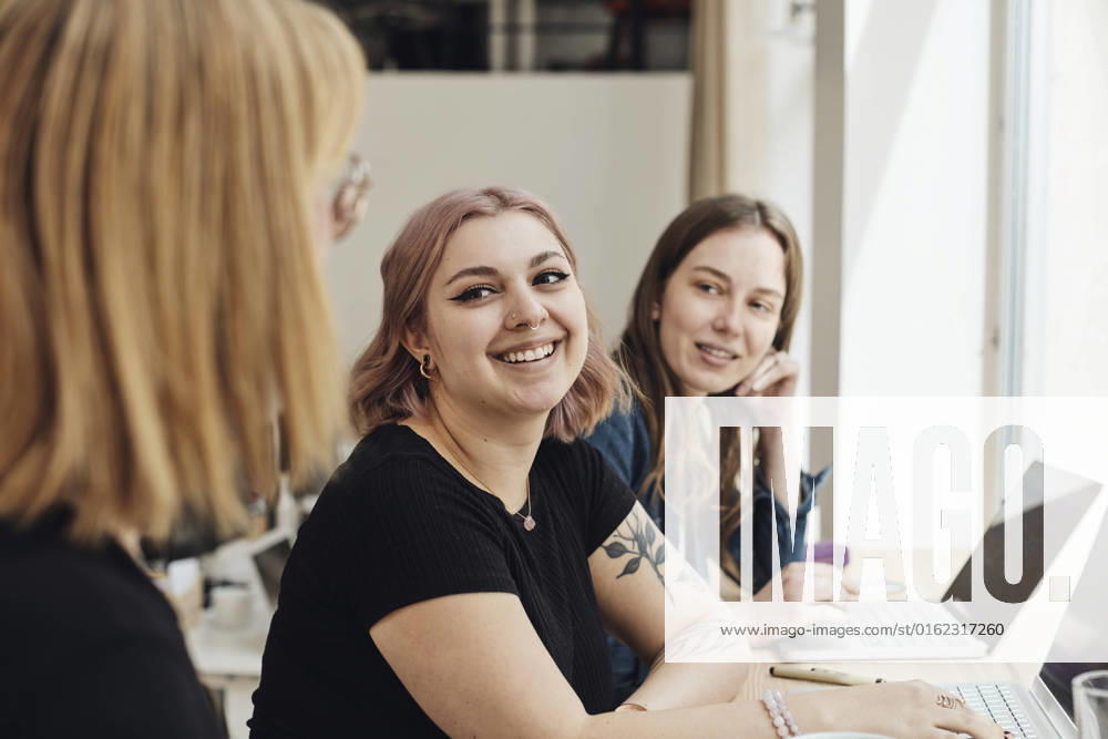 Smiling female entrepreneurs looking at colleague during meeting in office Sweden, Stockholm, model released, property released