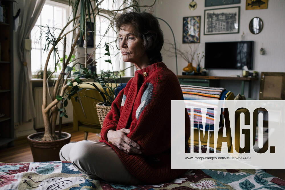 Depressed senior woman sitting alone on bed at home Germany, Berlin, model released, property released