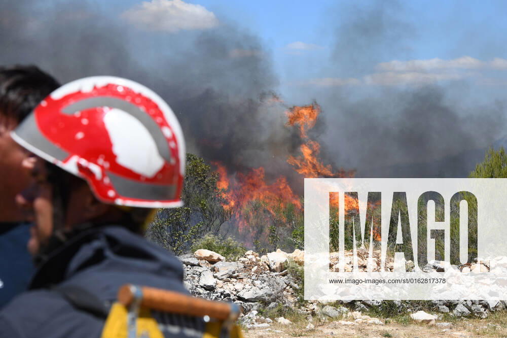 PXL_A fire near Vodice, Croatia Fire in an open area near the Velika Mrdakovica archaeological site in the Vodice hinterland, Croatia on July 13, 2022. About 30 firefighters with a dozen vehicles are on the ground, and two Canadairs joined the ground forces in extinguishing the fire. There are pine forests above, low vegetation, and endangered buildings. HrvojexJelavic PIXSELL