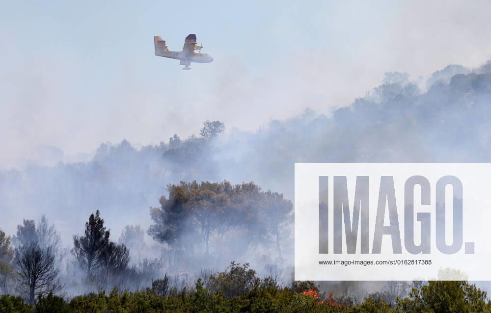 PXL_A fire near Vodice, Croatia Fire in an open area near the Velika Mrdakovica archaeological site in the Vodice hinterland, Croatia on July 13, 2022. About 30 firefighters with a dozen vehicles are on the ground, and two Canadairs joined the ground forces in extinguishing the fire. There are pine forests above, low vegetation, and endangered buildings. DuskoxJaramaz PIXSELL