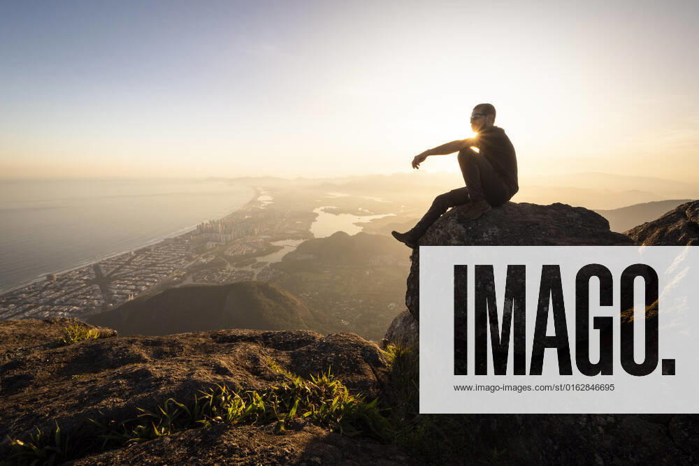 Man enjoying beautiful sunset view to city from rocky mountain top Rio de Janeiro, State of Rio de Janeiro, Brazil CR_GNUJ22070662-1004290-01 ,model released, Symbolfoto