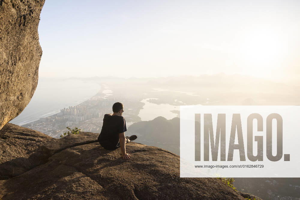 Man enjoying beautiful sunset view to city from rocky mountain top Rio de Janeiro, State of Rio de Janeiro, Brazil CR_GNUJ22070662-1004299-01 ,model released, Symbolfoto