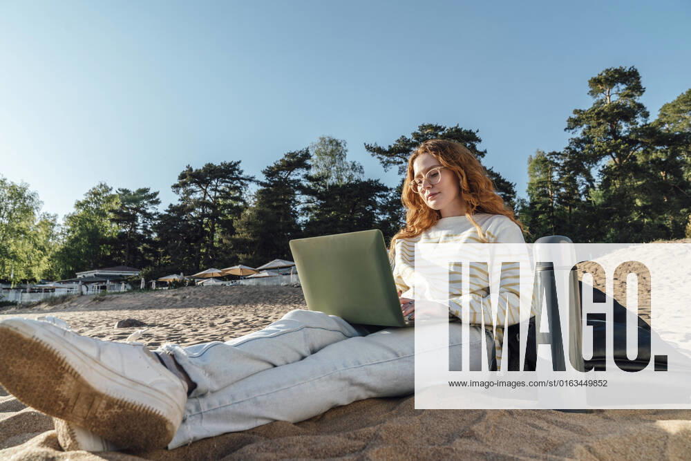 Woman e-learning over laptop at beach model released, Symbolfoto, VPIF06573