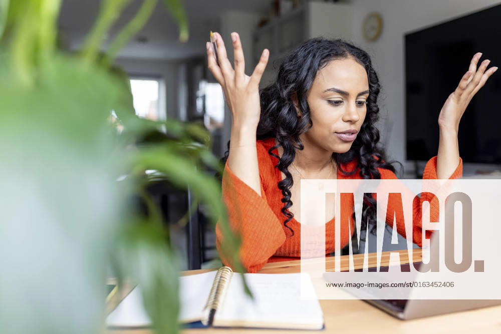 Woman gesturing and talking on video call over laptop at home office model released, Symbolfoto property released, WPEF05993