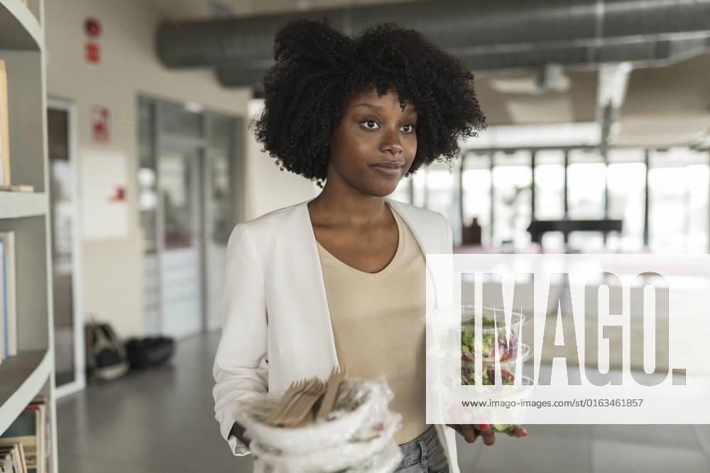 Young businesswoman with salad boxes standing in office model released, Symbolfoto property released, JCICF00173