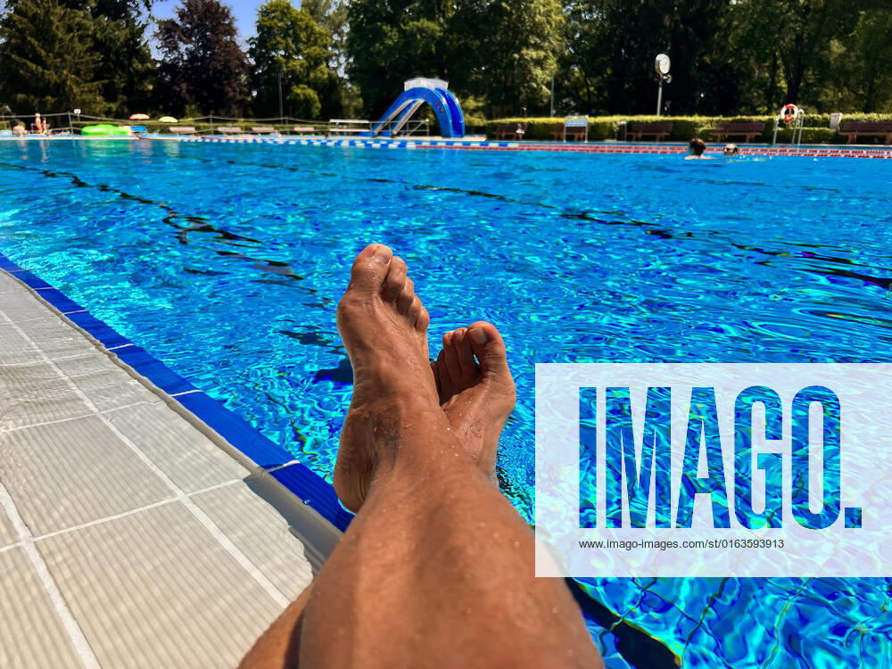 Swimming in the outdoor pool Bad Wörishofen Bavaria , a man sits by the pool at the water Model Release available 26 07 2022, Relaxing in the outdoor pool 26 07 2022, Relaxing in the outdoor pool