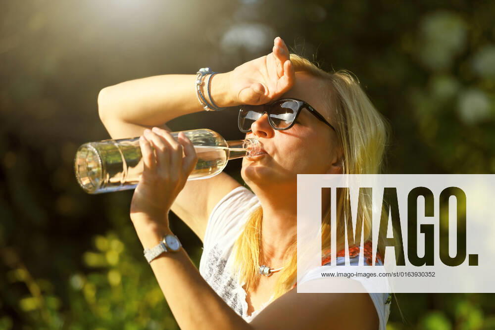 Woman in garden drinking water from bottle, symbol photo heat wave ** NUR FUER REDAKTIONELLE ZWECKE ** **