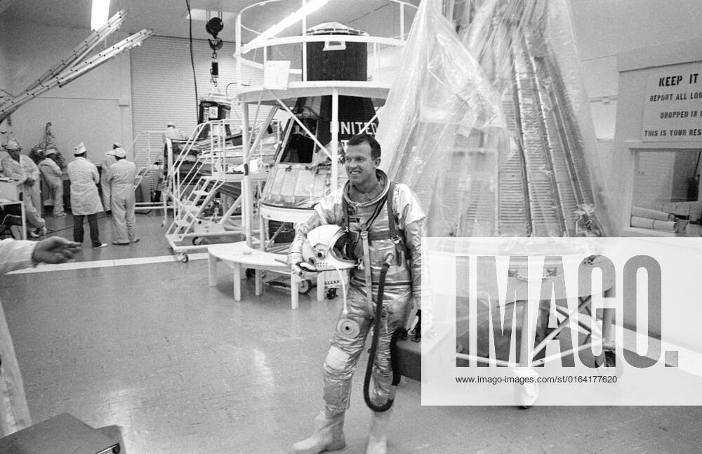 S63-03966 (1963) --- Astronaut L. Gordon Cooper Jr., prime pilot for the Mercury-Atlas 9 (MA-9) mission, carrying the portable air conditioner to his spacesuit, leaves Hanger S after completing the day s simulated flight tests.