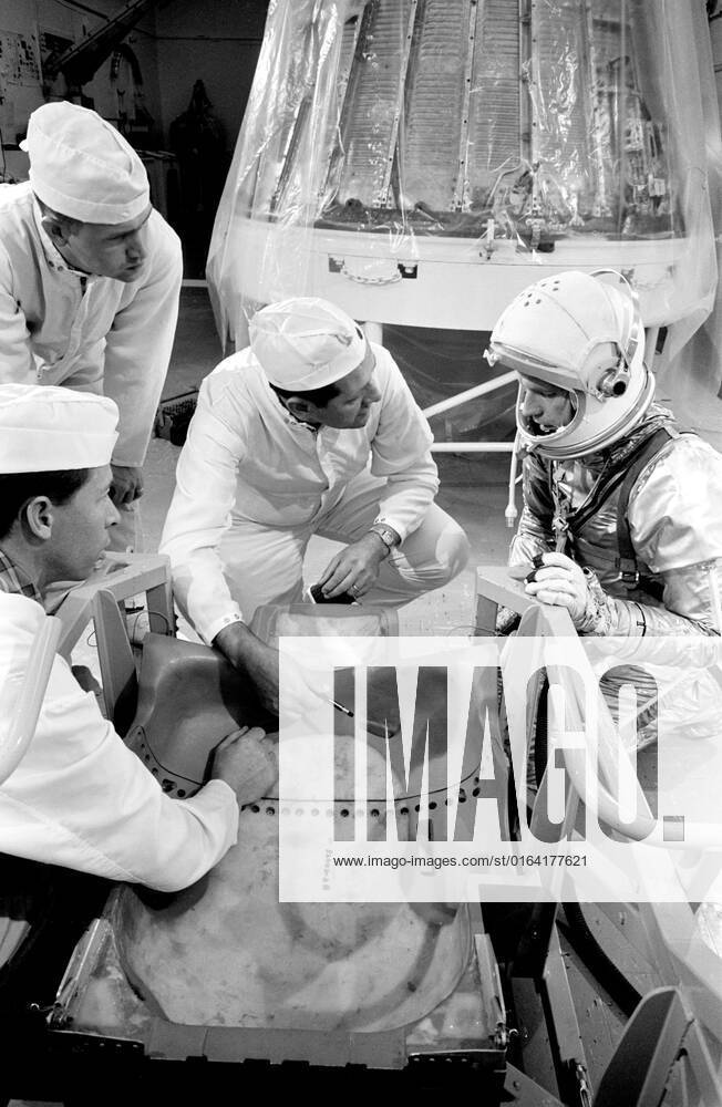 S63-03968 (1963) --- Astronaut L. Gordon Cooper Jr., prime pilot for the Mercury-Atlas 9 (MA-9) mission; Joe Trammel, MAC technician; A. Rochford, NASA suit technician; and C.R. Coyle, MAC technician, look over spacecraft couch.