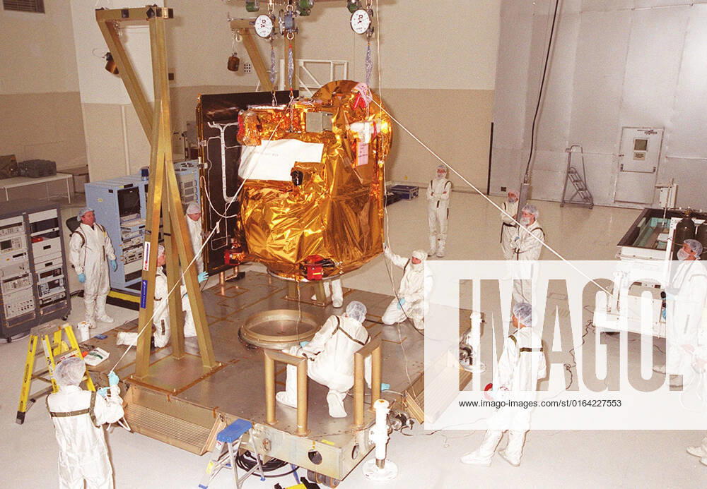 In the Spacecraft Assembly & Encapsulation Facility -2, workers help guide the <a href=http: mars.jpl.nasa.gov 2001 >2001 Mars Odyssey Orbiter < a>as it is lowered to a workstand. The Mars Odyssey Orbiter carries three science instruments: the Thermal Emission Imaging System (THEMIS), the Gamma Ray Spectrometer (GRS), and the Mars Radiation Environment Experiment (MARIE). THEMIS will map the mineralogy and morphology of the Martian surface using a high-resolution camera and a thermal infrared imaging spectrometer. The GRS will achieve global mapping of the elemental composition of the surface and determine the abundance of hydrogen in the shallow subsurface. The GRS is a rebuild of the instrument lost with the Mars Observer mission. The
