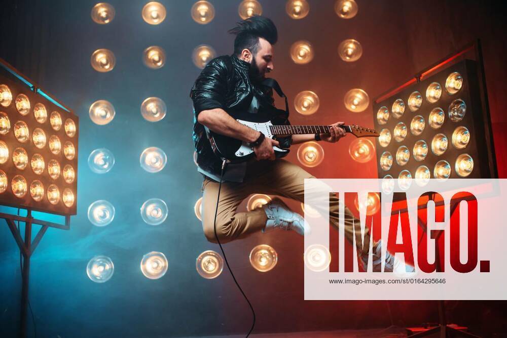 Male performer with electro guitar in a jump, Male performer with electro guitar in a jump on the stage with the decorations of lights. Music entertainment. Bearded musican song performing model released, Symbolfoto , 05.02.2020 02:30:45,